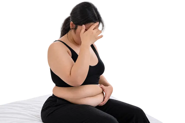 Woman seated with her hand to her forehead, reflecting weight and health challenges